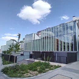 Edificio moderno con fachada acristalada, escaleras y zona ajardinada

