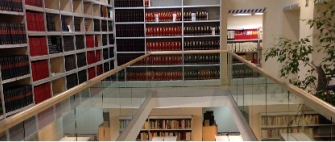 Vista interior de biblioteca moderna con estanterías, pasarela acristalada y libros