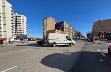 Vehículos cruzándose en la calzada de Antonio López a la altura de Camino de Perales, mientras un peatón cruza por donde no debe al no existir un semáforo cerca que le lleve al Metro.